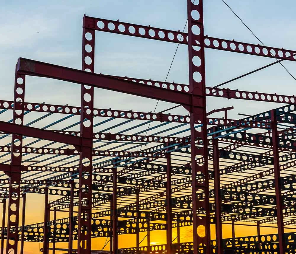 Stahlkonstruktion eines Industriegebäudes bei Sonnenuntergang.
