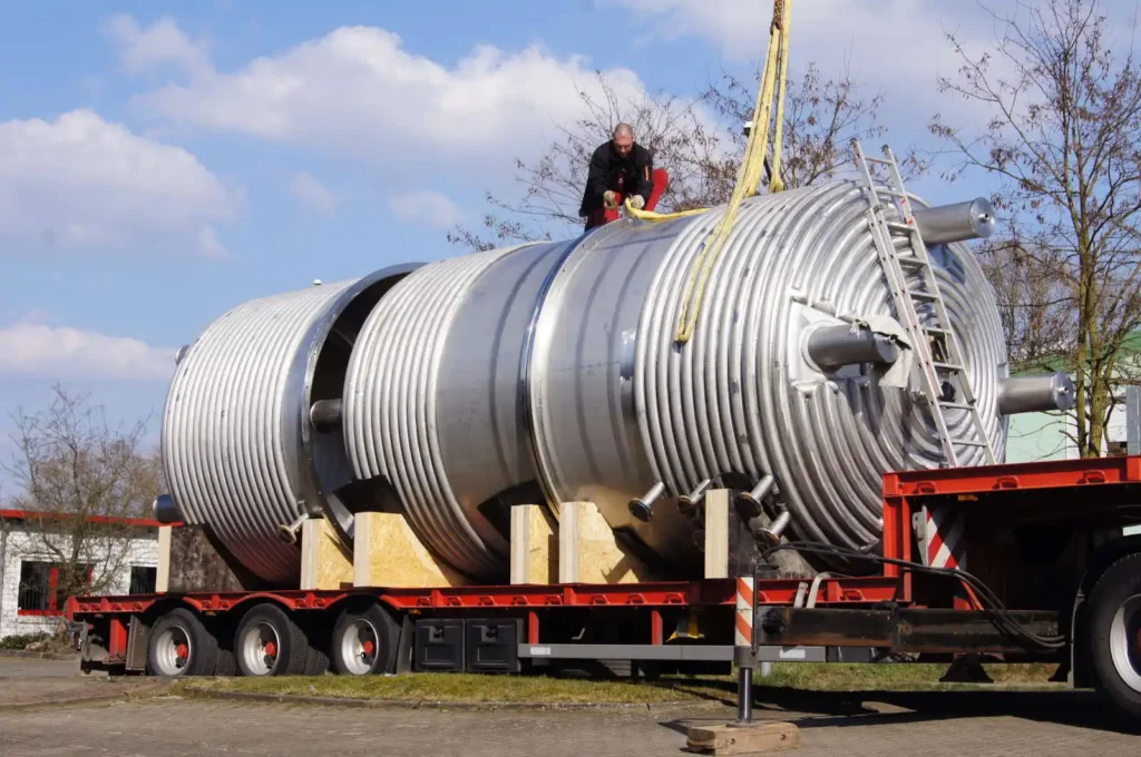 Ein großer Metallbehälter wird auf einem Lkw transportiert.