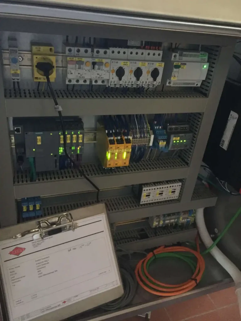 Elektroschaltkasten mit verschiedenen Komponenten und Kabeln in einer industriellen Umgebung.
