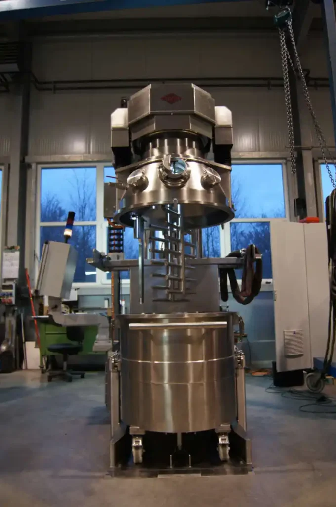 Edelstahl-Planetenmischer in einer Industrieumgebung mit zwei Fenstern im Hintergrund.